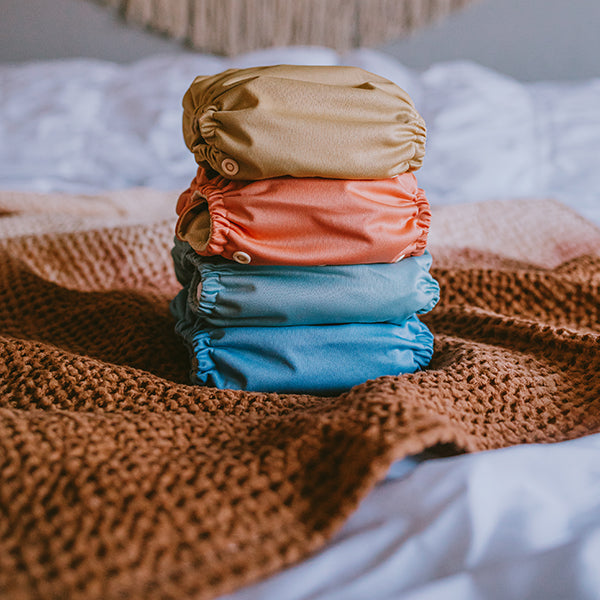 Reusable Cloth Diapers stack on a bed