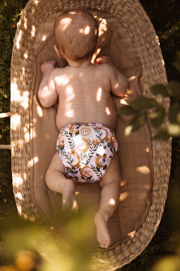 Baby wearing All In One Cloth Diaper in a basket in the sun. Lighthouse Kids Company