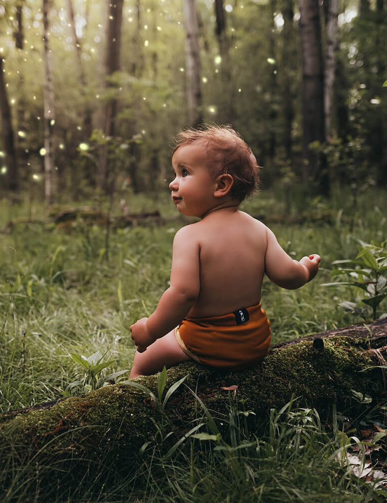 Baby in the woods using lighthouse kids company cloth diapers in woodland color